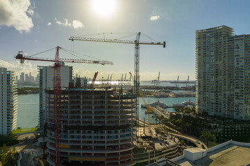 Fototapeta na wymiar Aerial view of new developing residense in american urban area. Tower cranes at industrial construction site in Miami, Florida. Concept of housing growth in the USA