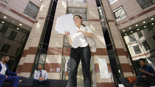 Young female executive has enough of paperwork and throws paper up in the air and walks out, in slow motion
