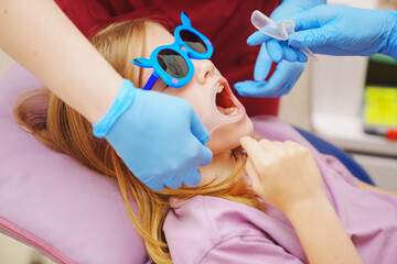 The pediatric dentist installs cheek and lip retractor for takes photos