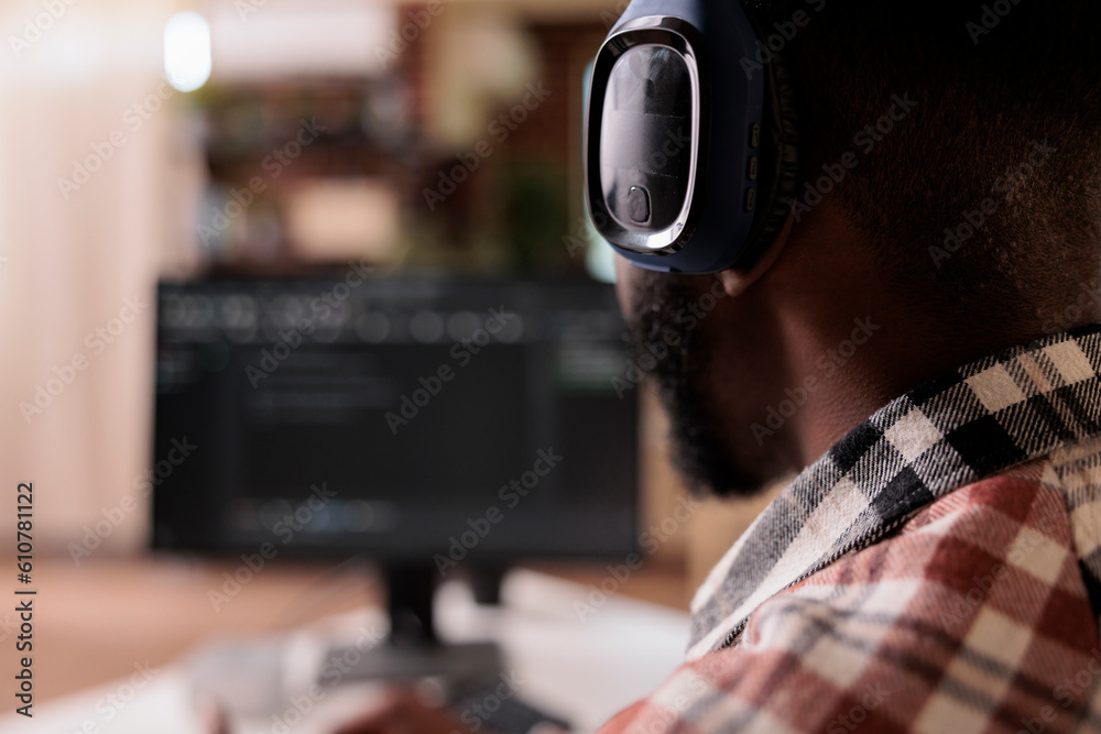 Poster closeup on freelance coder with wireless headphones listening to music while developing software on 