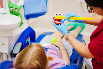 Cheerful pediatric dentist with a patient. training in proper brushing