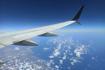 View through airplane window of commercial jet plane wing flying high in the sky. Air travelling concept