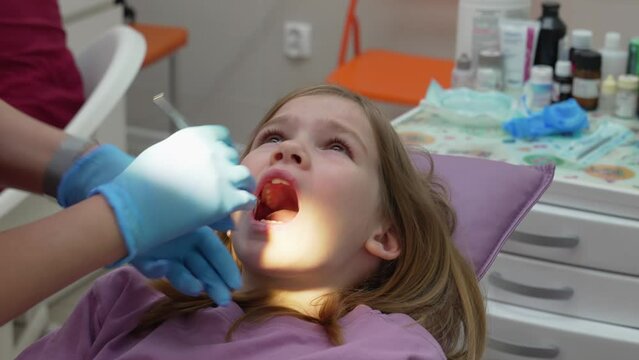 A pediatric dentist examines the teeth and oral cavity for a little girl.