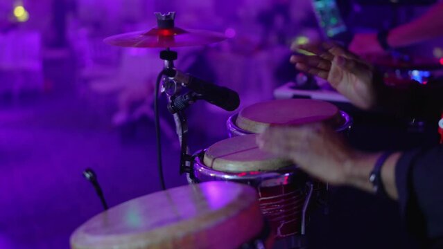 A man bangs his hands on the drums at a party or concert. A video without a face