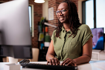 Smiling african american programmer relaxing looking at funny content on computer screen while...