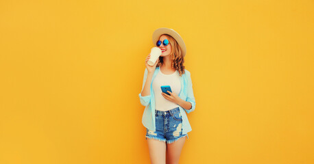 Happy smiling young woman 20s drinking coffee with smartphone looking away wearing summer straw hat, shorts on orange background - obrazy, fototapety, plakaty
