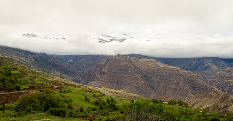Fototapeta premium Panoramic view of the cloud-covered mountains in a green valley