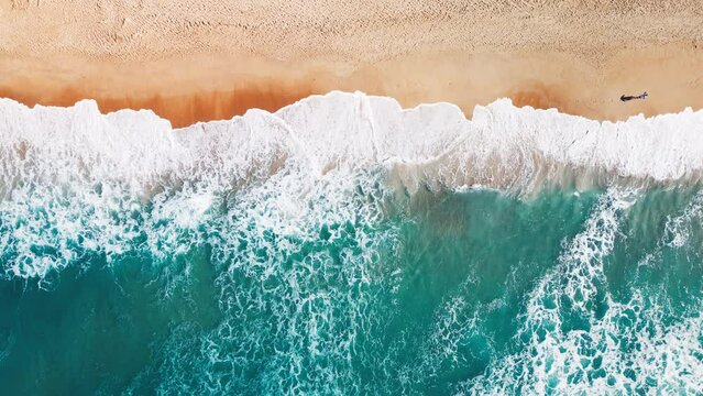 Aerial top down view of the sandy beach and crushing waves