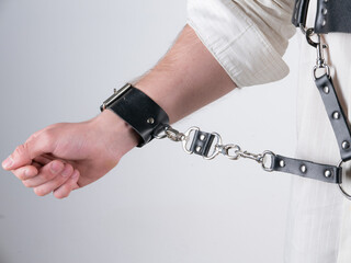 a white man with a short haircut and an athletic build in a shirt and a leather belt bdsm image on a light background