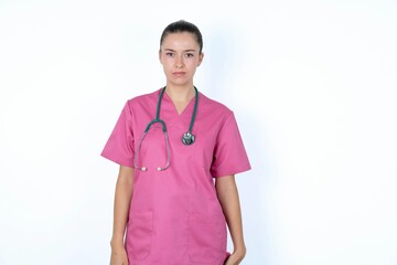 young caucasian doctor woman wearing pink uniform over white background frowning his eyebrows being displeased with something.