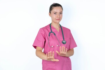 Afraid young caucasian doctor woman wearing pink uniform over white background , makes terrified...