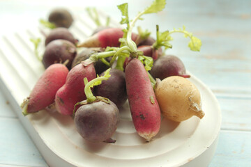 Fresh red radish bundle on chopping board on table 