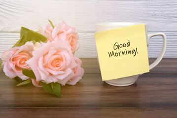 Pink rose and adhesive paper note on coffee mug with text - Good morning