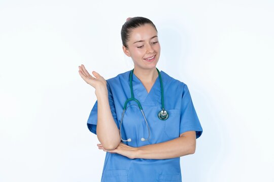 Overjoyed successful young caucasian doctor woman wearing medical uniform over white background raises palm and closes eyes in joy being entertained by friends