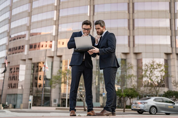 pondering two businessmen trading online. businessmen trading online outdoor.