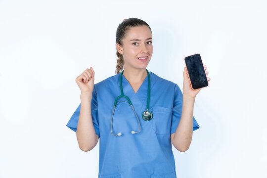 Photo of nice pretty young caucasian doctor woman wearing medical uniform over white background demonstrate phone screen hold hair tails