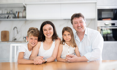Portrait of happy family - father and mother with two children at the table at home