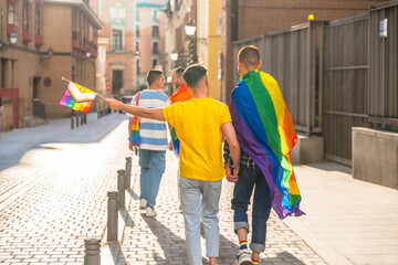 Gay pride party in the city, couples of men walking back to back towards the demonstration with rainbow flags, lgbt concept