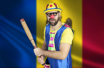 An insecure clown holds a bat in his hands against the background of the flag of Moldova