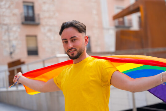 Attractive gay man with rainbow lgbt flag in the city, pride party and homosexual