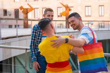 Friends waving and hugging at the demonstration with the rainbow flags, gay pride party in the city, lgbt concept