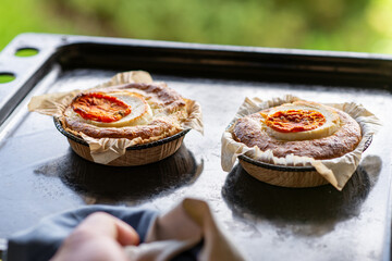casserole with cheese and tomato. Two servings of round casseroles on a baking sheet.