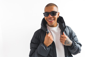 African American man in sunglasses and a puffer jacket smiling at the camera isolated against a...