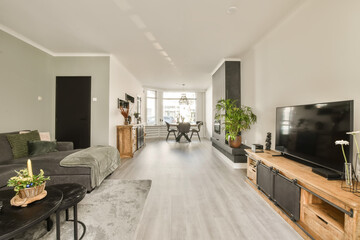 a living room with wood flooring and gray couches in the room is decorated with pots of plants