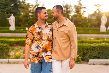 Romantic portrait of gay newlyweds walking and having fun at sunset in a park in the city....