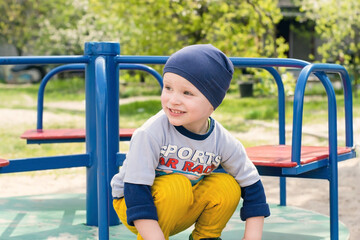 A boy on the playground. A child sits on a carousel