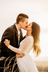 Pareja recien casada besandose felices con la luz de la puesta de sol, con anillo de matrimonio en...