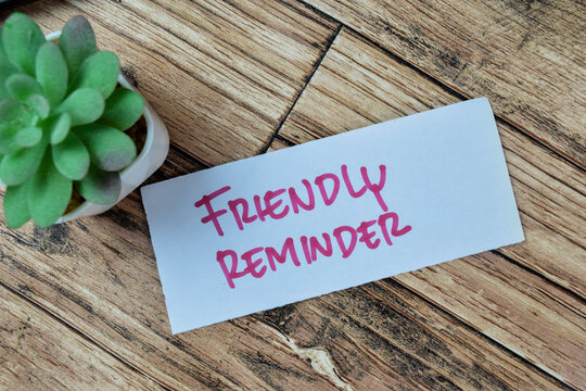 Concept of Friendly Reminder write on sticky notes isolated on Wooden Table.