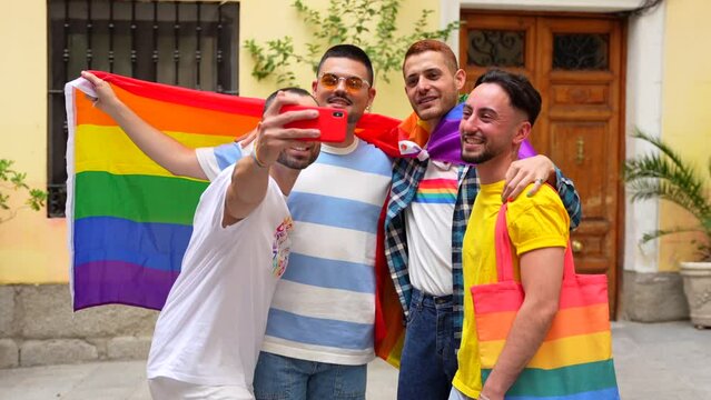 Homosexual male friends having fun at gay pride party taking a selfie, diversity of young people in the city, road to the demonstration with the rainbow flags, lgbt concept