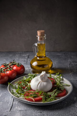Burrata cheese with tomatoes, arugula and pesto sauce on a marble table.