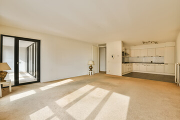 an empty living room with white walls and beige carpet, there is no one person in the room to be seen