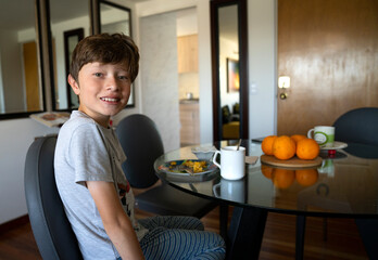 Boy drinking orange juice and eating eggs for breakfast