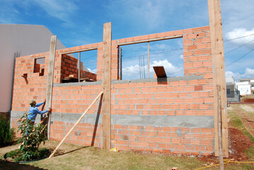 pedreiro construtor edificando parede de tijolos em obra 