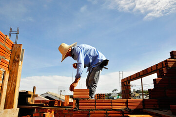 pedreiro construtor edificando parede de tijolos em obra 