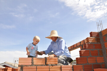 pai e filho construindo parede de tijolos 