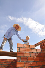 avô e neto construindo parede de tijolos em construção 