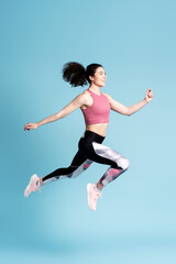 Fototapeta na wymiar Full size young strong sporty athletic woman doing gym exercises, jumping high, running