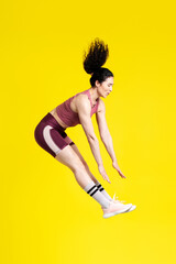 Vertical studio portrait of a successful strong sportswoman jumping high up