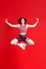 Female athlete in activewear, determined sportswoman, closed eyes, meditating and jumping