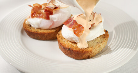 poached egg toast topped with hollandaise sauce. benedict egg. serving breakfast on a white background. sunny day. angle view.