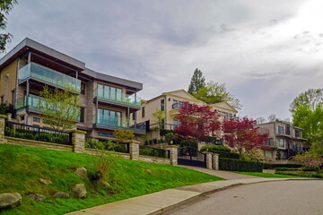 Fototapeta na wymiar Residential district in the Burnaby Lake Park area, private houses with sundecks, trees and garden on the background of blue cloudy sky