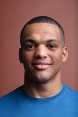 Afro-American individual, muscular, smiles on brown backdrop