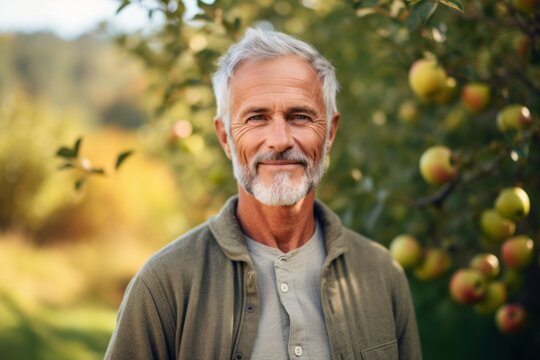 Medium shot portrait photography of a pleased man in his 60s that is wearing a chic cardigan against a sunlit apple orchard with ripe apples on trees background .  Generative AI