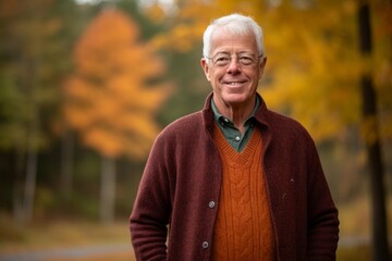 Obraz premium Portrait of a senior man standing in the park with autumn leaves in the background