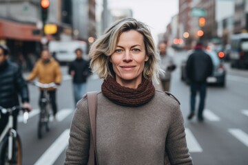 Fototapeta premium beautiful middle aged woman walking on street in city and looking at camera
