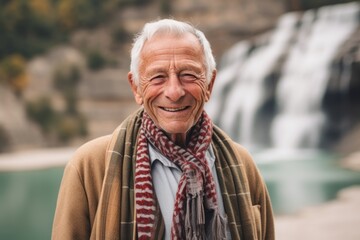 Portrait of a senior man with a scarf in front of a waterfall